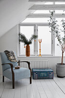 Old armchair, suitcase and room tree in the attic room with white floorboards, Christmas decoration on windowsill