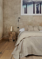 Double bed and tree trunk stool in a bedroom with sand colored walls