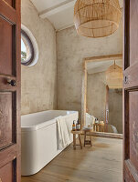 Large mirror and bathtub in the bathroom with sand-coloured walls