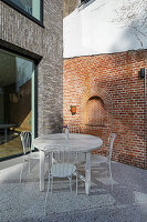 Round table and chairs on terrace with terrazzo floor and brick wall