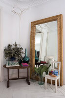 Large mirror leaning against the wall, wooden chair and table in the corner of the room