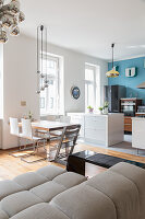 A kitchen with a light-blue wall, a dining area and a couch in an open-plan living room