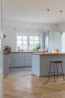 An open-plan, blue-grey kitchen with a breakfast bar