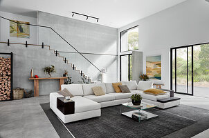 White sofa combination in high-ceilinged open-plan interior with staircase on back wall
