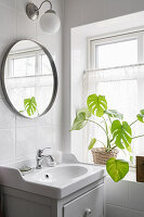 bathroom vanity with integrated sink, round mirror and houseplant in the bathroom