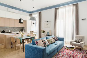 Einbauküche mit hellen Fronten, Essbereich und Sitzbereich mit Sofa in hellem Wohnraum