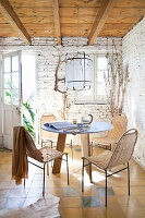 Round table with chairs and garden access in a room with a whitewashed brick wall