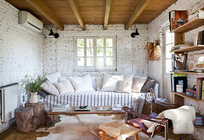 Sofa with cushions and shelves in room with whitewashed brick wall
