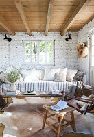 Sofa with cushions and coffee table in a room with a whitewashed brick wall