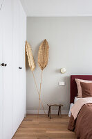 Palm leaves used as decorations next to fitted wardrobe in bedroom