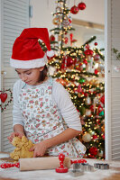 Girl wearing Father Christmas hat making biscuit dough