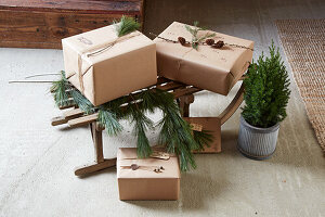 Weihnachtsgeschenke auf Holzschlitten mit Tannenzweigen und kleiner Topfzypresse