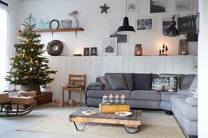 Wohnzimmer mit Weihnachtsbaum und Adventskerzen, einer Eckcouch und Paletten-Couchtisch
