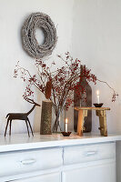 Winter decoration with berry branches and candles on a white chest of drawers