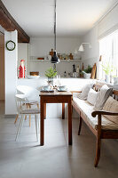 Heller Essbereich mit Holztisch, weißen Stühlen und Sitzbank am Fenster