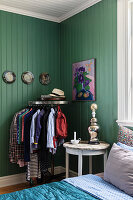Clothes rack in bedroom with green-painted wooden walls
