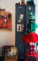 Girl in colorful clothes looking at Christmas decorations on a metal cupboard