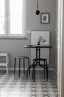 Slender black table and stools on tiled floor