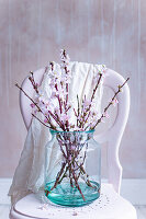 Blossom in green glass vase on pink chair