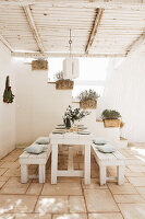 Gedeckter Holztisch mit Sitzbänken auf mediterraner, überdachter Terrasse