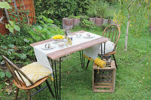 Gartentisch mit Dekos aus Birkenrinde, zwei Stühle und Holzkiste
