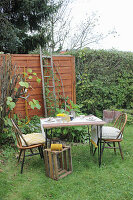 Gartentisch mit Dekos aus Birkenrinde, zwei Stühle und Holzkiste