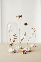 Dried flowers with gold leaf in modelling clay, under glass cover