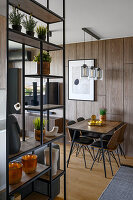 Shelves used as room divider and small dining area next to wood panelling