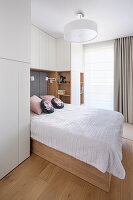 Double bed in light bedroom with built-in wardrobes