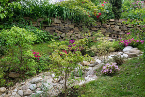 Sommerlicher Garten mit Natursteinen und Trockensteinmauer