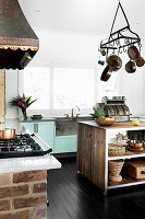 Kücheninsel, darüber Topfaufhänger aus Gusseisen, im Hintergrund Küchenzeile mit Betonarbeitsplatte