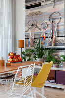 Esstisch mit verschiedenen Stühlen, Wandteppich und Traumfänger