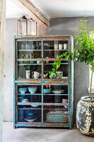 Vintage crockery cupboard with glass doors under wooden beams in the kitchen