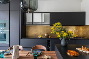 Modern kitchen with golden backsplash, dining table and yellow flowers