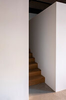 Minimalist wooden staircase and thick white walls