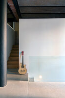 Guitar leaning against wall next to staircase with wooden steps