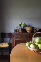 Wooden table with fruit basket and antique cupboard