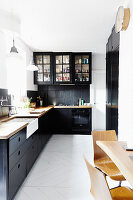 Modern kitchen with black wall tiles and cabinets with dining area