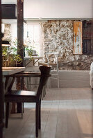 Dining area with rustic stone wall, wooden floorboards and wooden furniture