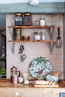 Wall shelves with storage jars and coffee press and cups on kitchen worktop