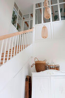 Hanging rattan lamps above white vintage cupboard next to staircase