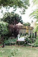 Filigree chairs and table with swan figurine in the garden