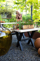 Tisch mit Pflanzkasten, Ballonflasche und Skulptur auf der Terrasse