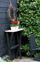Narrow table with flower pot against a black-painted wooden wall