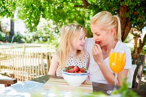 Mädchen mit der Mutter, die Erdbeeren isst