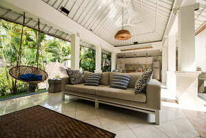 Open living area in a tropical luxury home with couch and hanging chair