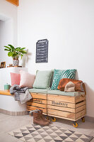 Bench made from wooden crates with cushions and decorative plant