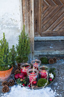 Adventskranz mit Windlichtern, Moos und roten Äpfeln in Vintage Schale vor Hauseingang