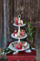Romantic tiered dessert stand with lanterns, red balls, walnuts, and gingerbread outdoors