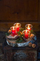 Windlichter mit roten Kerzen auf weihnachtlich dekorierter Baumscheibe